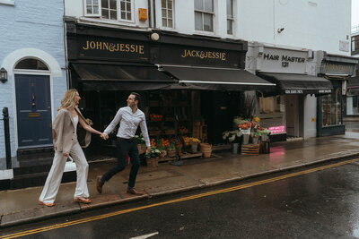 couple walking in street under during london engagement photos, captured by Elsie Goodman, an NYC and destination engagment photographer
