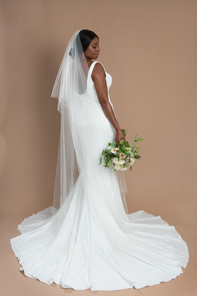 Bride wearing a chapel length veil with blusher and holding a white and blush bouquet