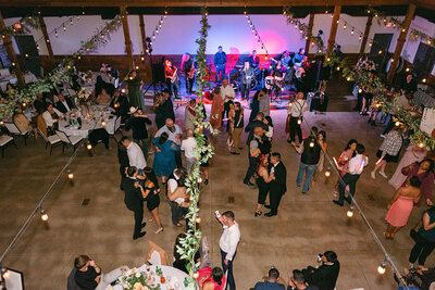 Overhead view of a full dance floor with guests under string lights and live band at a high-end editorial wedding reception in Austin, Texas.