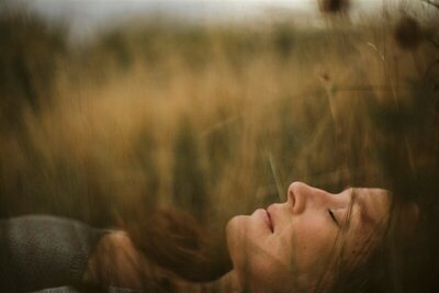 Woman laying in tall grass embodying self