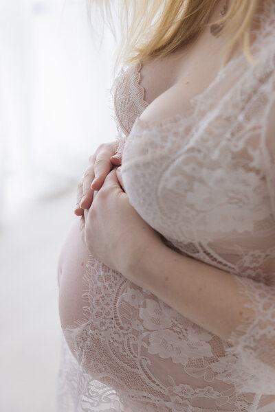 Gravid kvinne fotografert i studio Landmark. Iført hvit blondetopp.