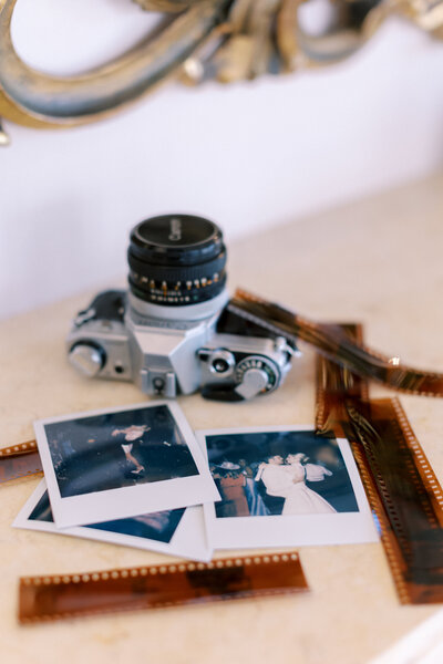 polaroids and film strips on a shelf with a film camera