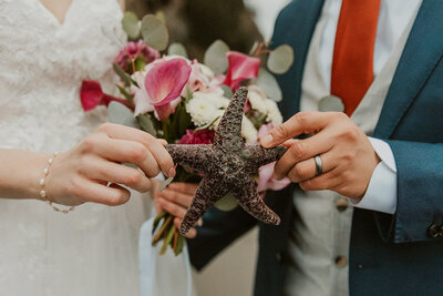 Couple in wedding attire holding a starfish on the Oregon Coast