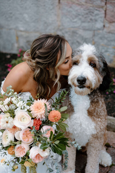 bride kissing dog on her wedding day