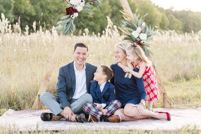Mother, father, and two young children smile for family photo in a field