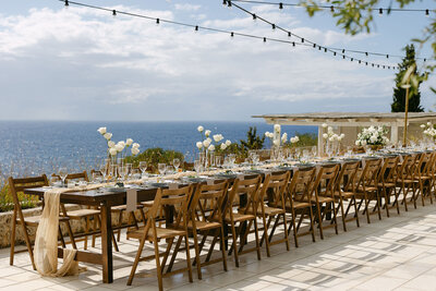 Elegant tablescape with floral centrepieces overlooking the sea, designed for Ionian weddings and events in Greece.