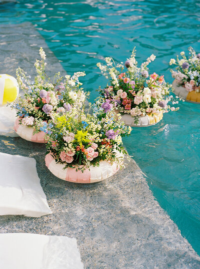 Floating floral arrangements in a pool, adding playful, artistic detail to an outdoor Austin wedding celebration planned with creativity.
