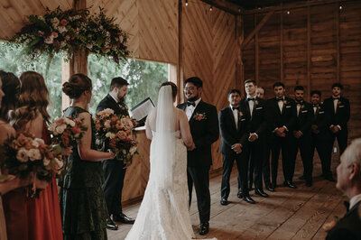 Bride and groom holding hands at a wedding ceremony surrounded by family