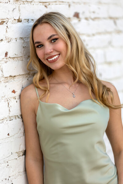 A blonde senior sits on a step at her home.