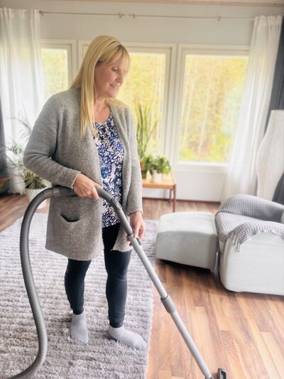 Kotihoitaja imuroimassa asiakkaan luona ja huolehtimassa kodin siisteydestä