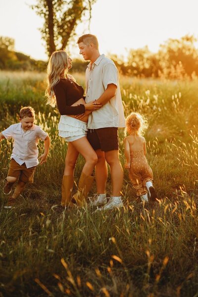 big brother holds baby brother while giving him a kiss on the head.