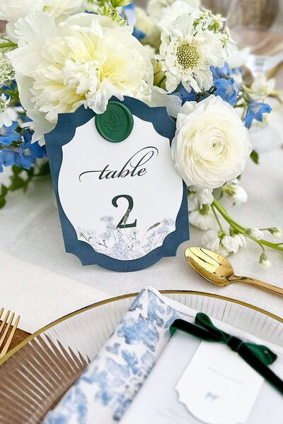 Blue velvet-trimmed wedding table number with floral border and green floral wax seal for a luxury wedding in Jackson, WY.