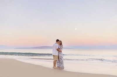 Couple stands close touching foreheads barefoot on the beach in Maui