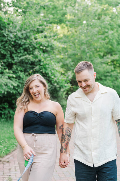 Engaged couple walk their dog during their engagement session at Anchorage Trail in Louisville