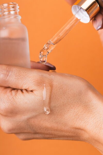 Dripping clear syrum on clean hand with an orange background