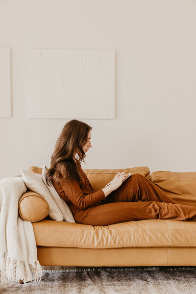 A UGC content creator cozied on the couch on her iPad