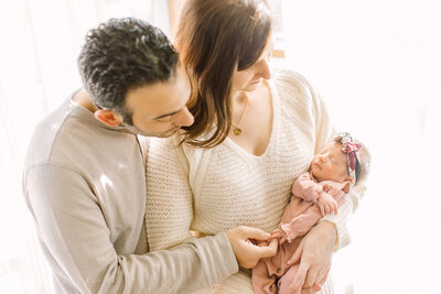 Newborn photography in Kansas City: mom and dad hold their newborn daughter for their studio photoshoot by Jeanna Hayes