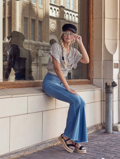 senior girl sitting on a ledge in front of a store glass window