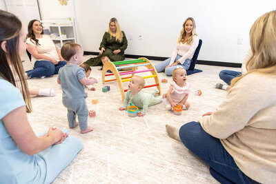 Group of babies playing in a circle while their moms watch