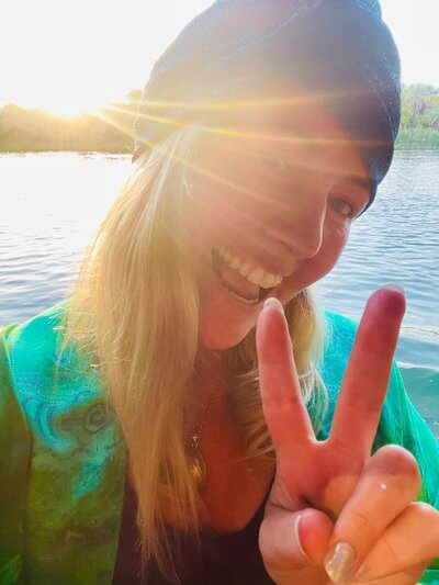 Katie, spiritual entrepreneur coach, smiling with sunlight beaming through the background, radiating warmth and positivity.