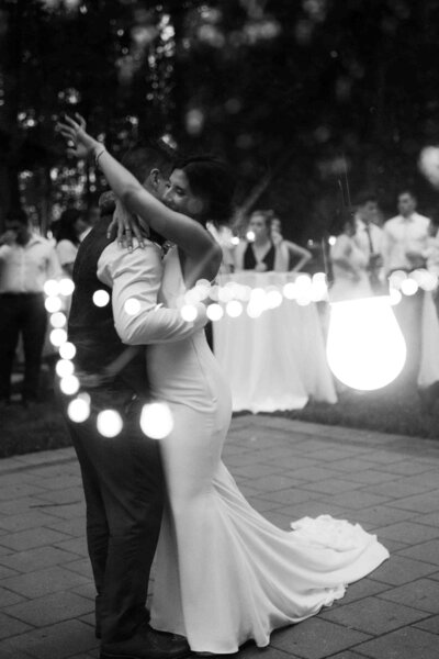 bride and groom first dance at reception with string lights outside