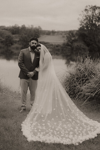 A moody black and white image of a bride and groom on the riverbank at their Bellingen elopement