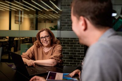 Woman sitting in a corporate boardroom with a laptop looking at a client 