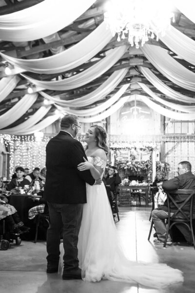Bride and groom sharing a first dance in a warmly lit barn venue