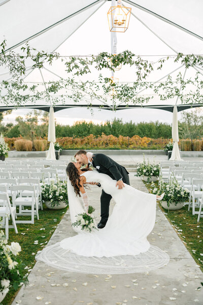 groom dipping bride for a big kiss in isle, wedding cake topper