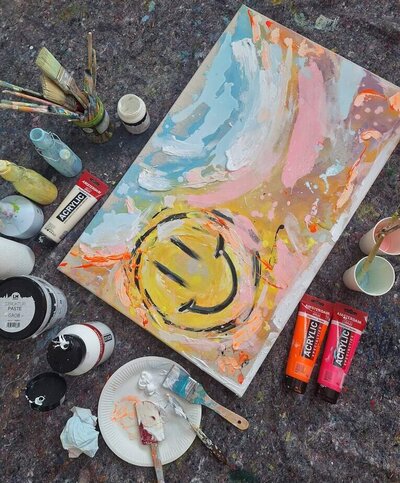 Happiness Is Energy ein farbenfrohes Acryl Kunstwerk zwischen Pinseln, Farben und Strukturpaste.