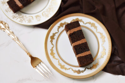 A slice of chocolate truffle wedding cake on an ornate gold plate with a fork