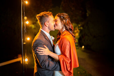 Pittsburgh wedding photo of bride and groom kissing next to string lights at a wedding at Phipps conservatory in Pittsburgh PA
