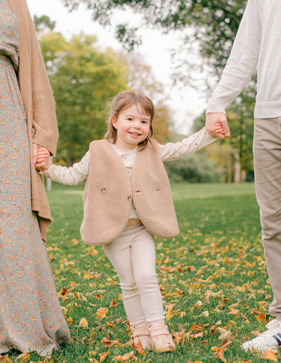 A little girl smiles during a fall photoshoot in Vondelpark in Amsterdam, Netherlands.