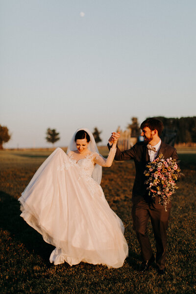 bride and groom walking through field