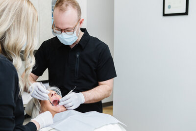 Dr. Merrill Tyson performing dental surgery at Peak Prosthodontics in Lethbridge reminds patients that mild blood staining in saliva is normal after surgery, while profuse bleeding is rare.