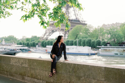 Kim-Trang sits on a bridge in front of the Eiffel Tower