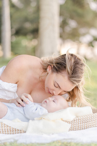 mother smelling newborn babys cheek during an outdoor family session at Shorncliffe Pier, Brisbane.