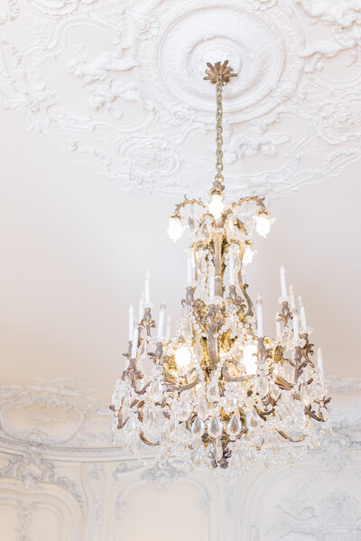 Interior shot of a fancy chandelier on an ornate ceiling