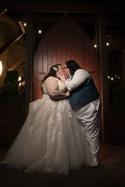 A newlywed couple standing close together kissing 