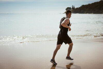 Active middle-aged man running on the beach representing improved energy and vitality through testosterone therapy at Wellness and Hormone Health in Centennial, CO
