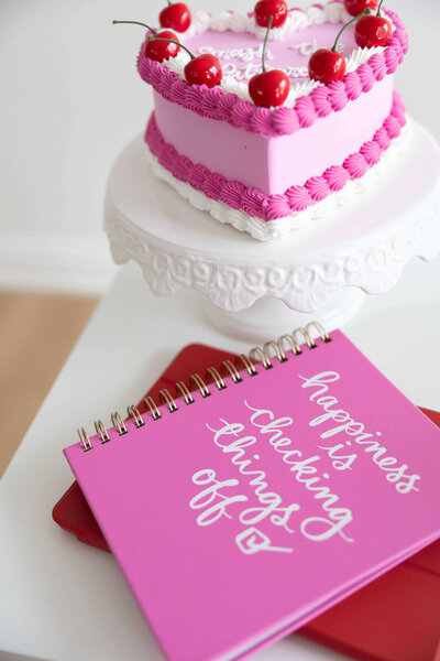 A pink notebook that says "happiness is checking things off."