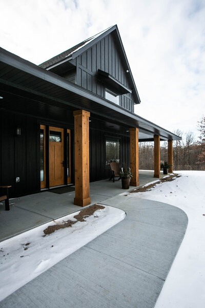 Custom Minnesota Home built by Cornerstone Custom Builds with black siding and wood pillars.