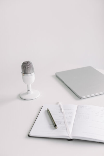 white microphone, journal and laptop on desk