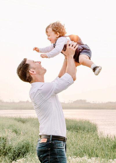 father lifting sun above him during family photo session