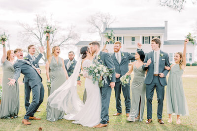 Bride and groom kissing with bridal party cheering