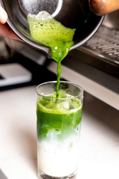 Barista pouring fresh matcha over ice at Grain Artisan Bakery & Craft Coffee in Snohomish, Washington.