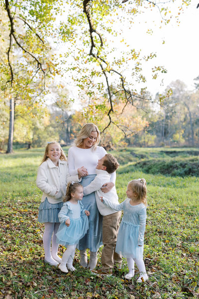 Stephanie Houseal laughs with her four children in a sunlit field. A personal moment from the artist behind Moments in Light Photography.