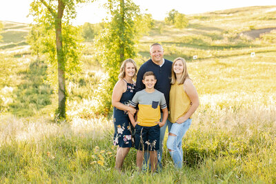 A white family of four wearing yellow and navy standing in a field