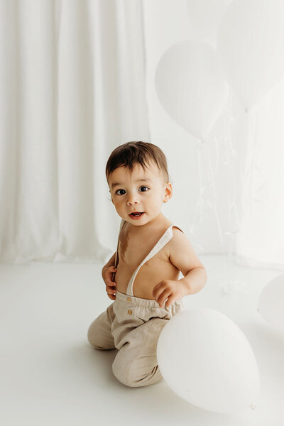 One year old boy is photographed playing with balloons for his 1st birthday photo session with Vancouver Washington photographer