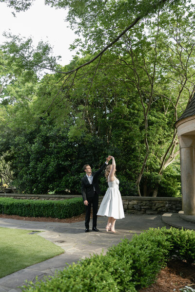 bride and groom walking down estate path twirling the bride